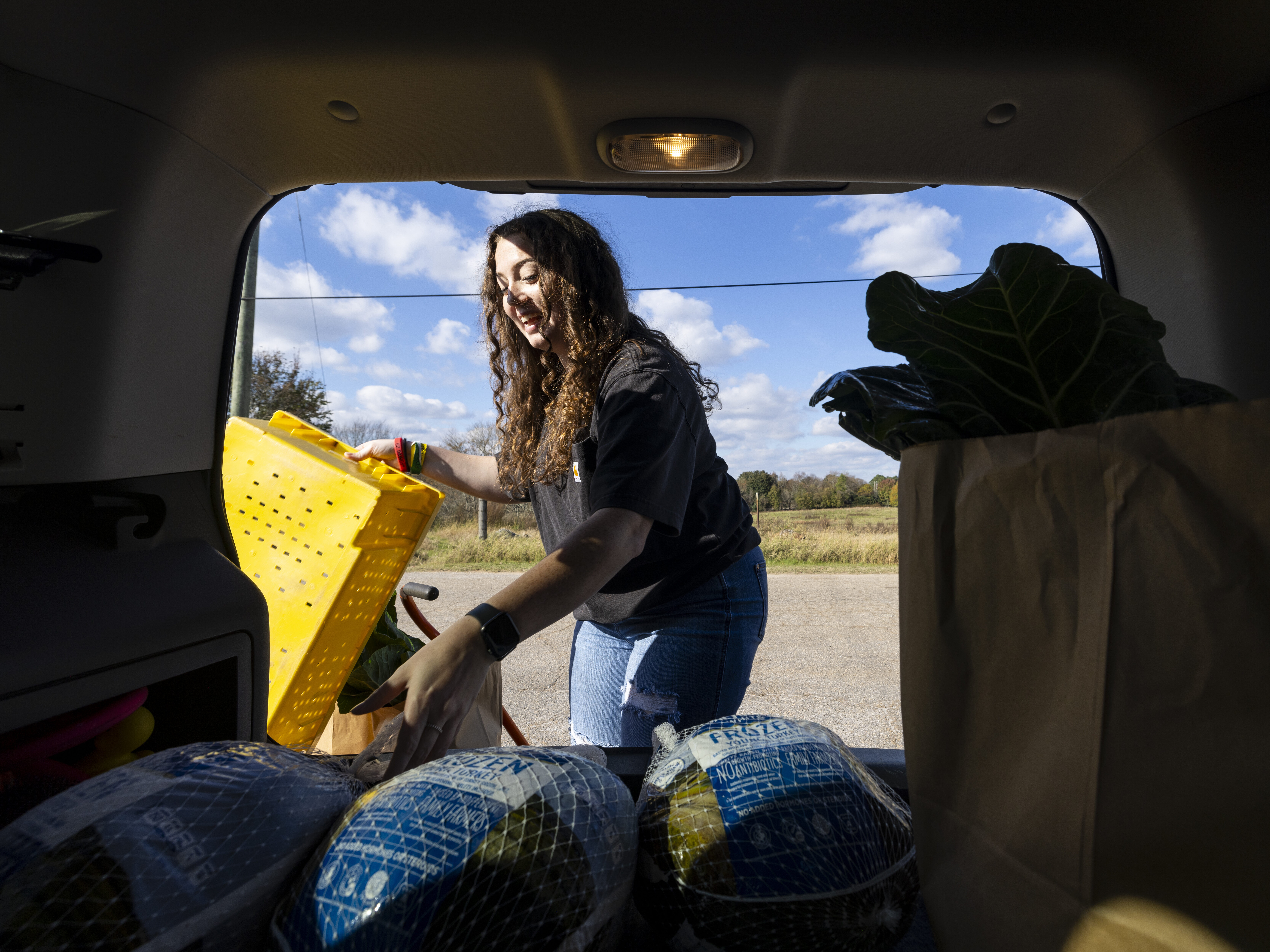 A UGA female volunteer is unloading frozen turkeys from the back of a SUV.